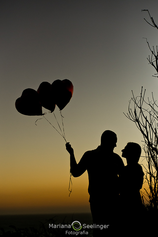 casal com balões de coração ao por do sol em ensaio de casal por Mariana Seelinger Fotografia em Arraial do Cabo - RJ