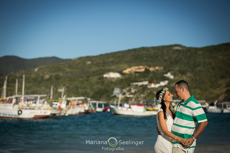 O casal abraçado com o mar e os barcos ao fundo em fotografia por Mariana Seelinger