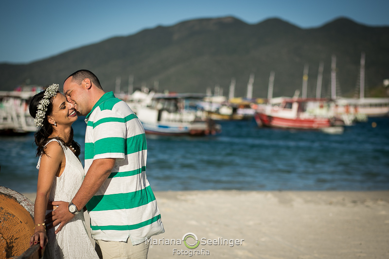 O casal se beija com o mar as montanhas e os barcos de pesca de fundo em Arraial do Cabo - RJ