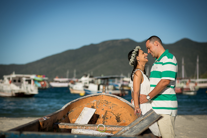 O casal se olha apaixonado ao lado de um barco em ensaio de casal por Mariana Seelinger Fotografia