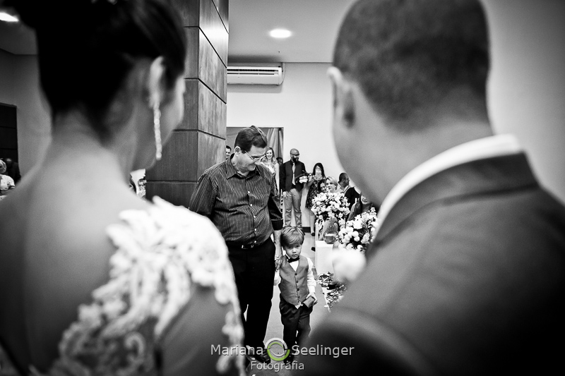 Os noivos de costas para a fotógrafa observando a chegada do pajem em casamento no Rio de Janeiro - RJ por Mariana Seelinger