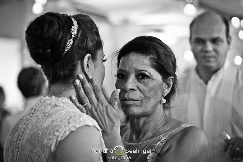 a mãe da noiva emocionada segura o rosto de Natalia em fotografia de casamento por Mariana Seelinger em Niterói - RJ