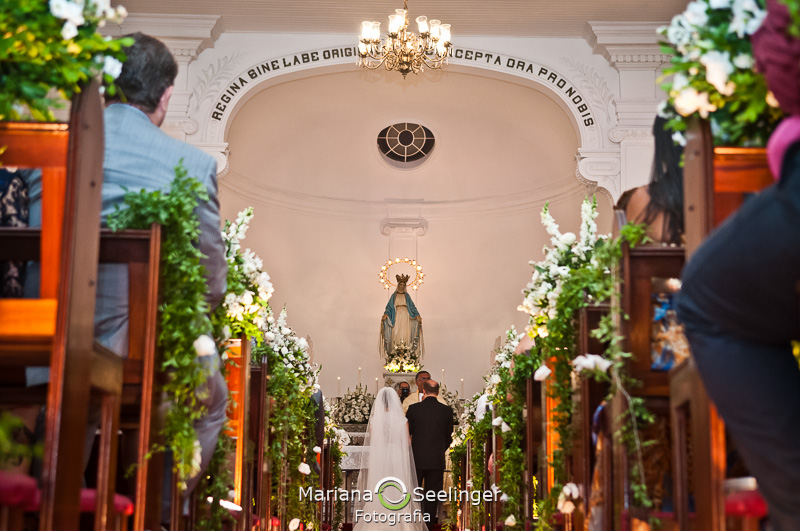 visão dos noivos e das flores pelo corredor diante do altar por Mariana Seelinger Fotografia em Niterói - Rj