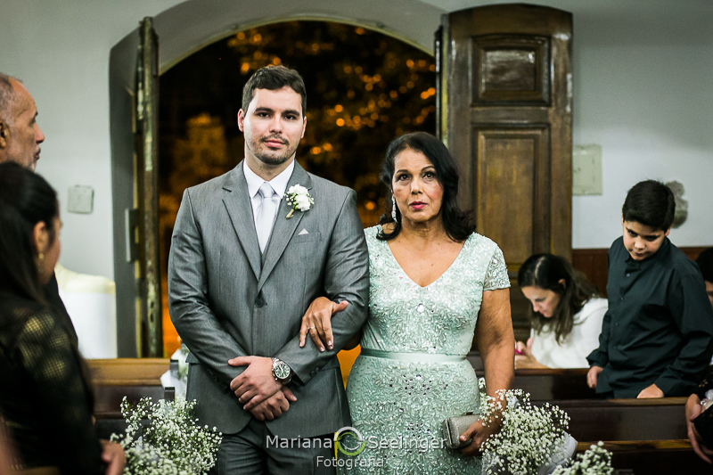 o noivo adentra a igreja acompanhado pela mãe em casamento na cidade de Niterói - RJ por Mariana Seelinger Fotografia
