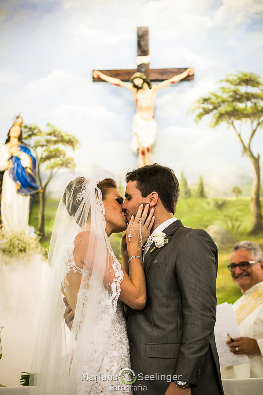 os noivos Thais e Adriano se beijam em frente ao altar