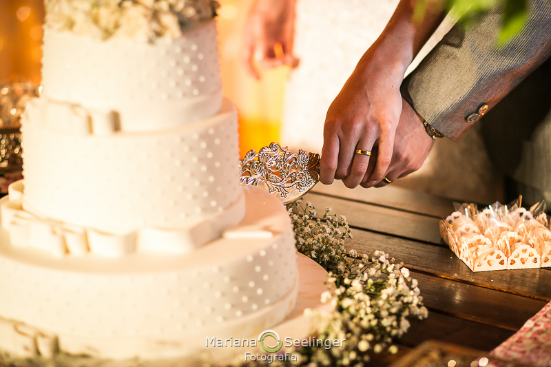 o corte do bolo de casamento pelas mãos unidas do casal