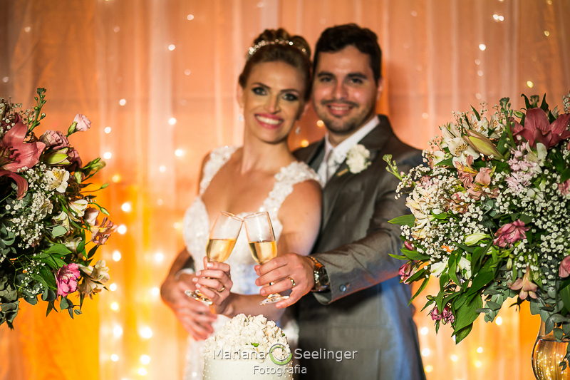 os noivos posam com as suas taças de champange em fotografia por Mariana Seelinger