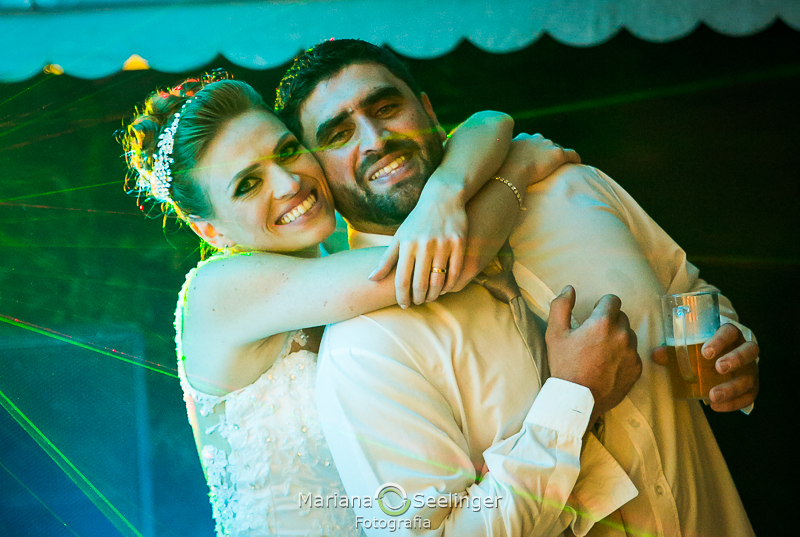 a noiva pendurada no pescoço do noivo sorridente em seu casamento em Niterói - Rj