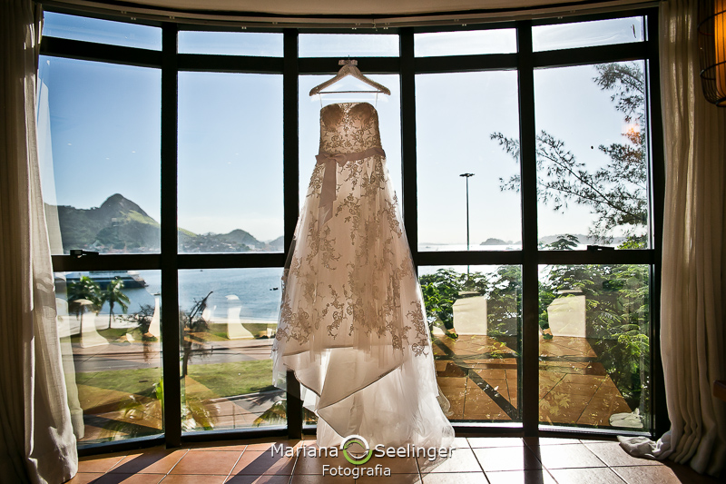 o vestido da noiva na fotografia de casamento Niterói por Mariana Seelinger pendurado com o mar de fundo
