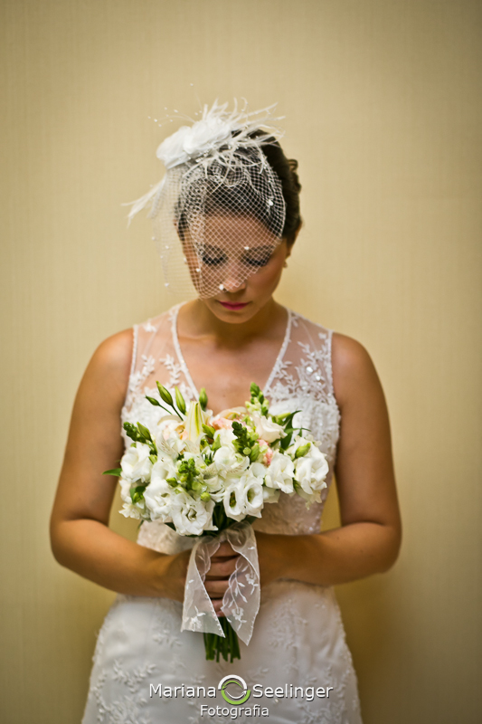 Noiva com vestido de renda segurando bouquet de flores claras em casamento registrado por Mariana Seelinger Fotografia de Casamentos e Familias em Niterói RJ