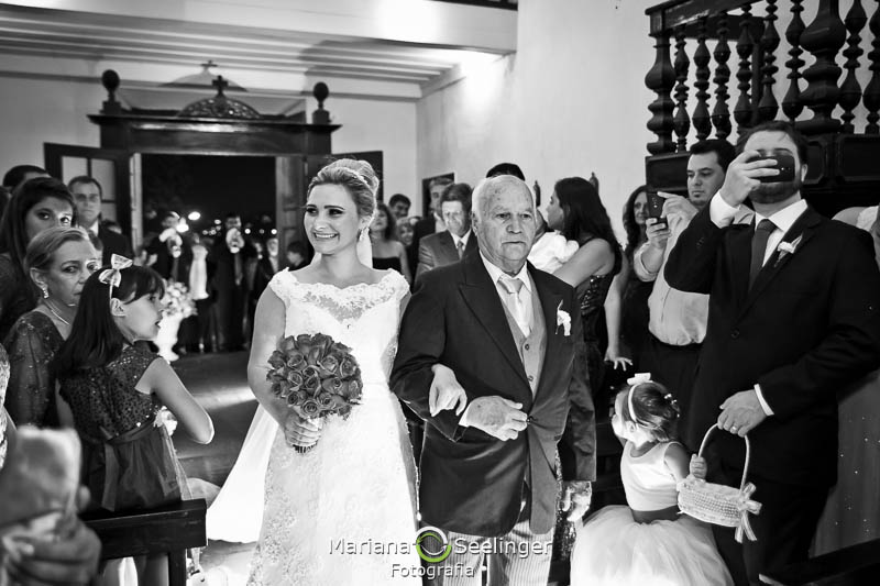 Foto em preto e branco da noiva sendo acompanhada pelo pai até o altar em casamento registrado por Mariana Seelinger Fotografia de Casamentos e Familias em Niterói RJ