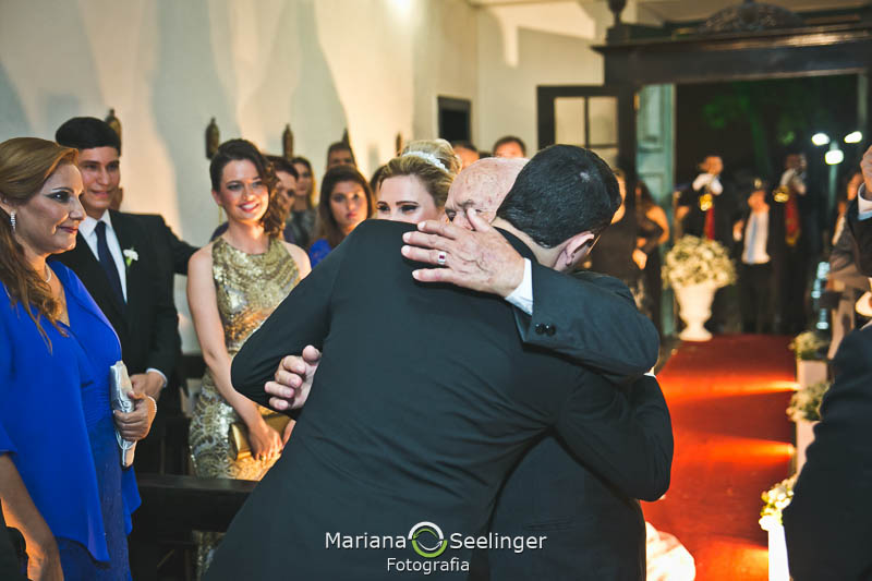 Noivo sendo cumprimentado pelo pai da noiva no altar em casamento registrado por Mariana Seelinger Fotografia de Casamentos e Familias em Niterói RJ