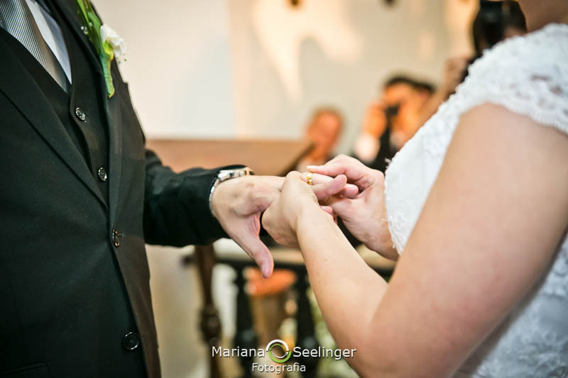 Noiva botando aliança no dedo do noivo em casamento registrado por Mariana Seelinger Fotografia de Casamentos e Familias em Niterói RJ