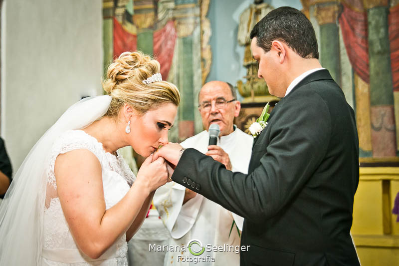 Noiva beijando a mão do noivo em altar de igreja em niterói em casamento registrado por Mariana Seelinger Fotografia de Casamentos e Familias em Niterói RJ