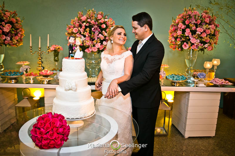 Noivos cortando bolo de casamento branco de 4 andares em casamento registrado por Mariana Seelinger Fotografia de Casamentos e Familias em Niterói RJ