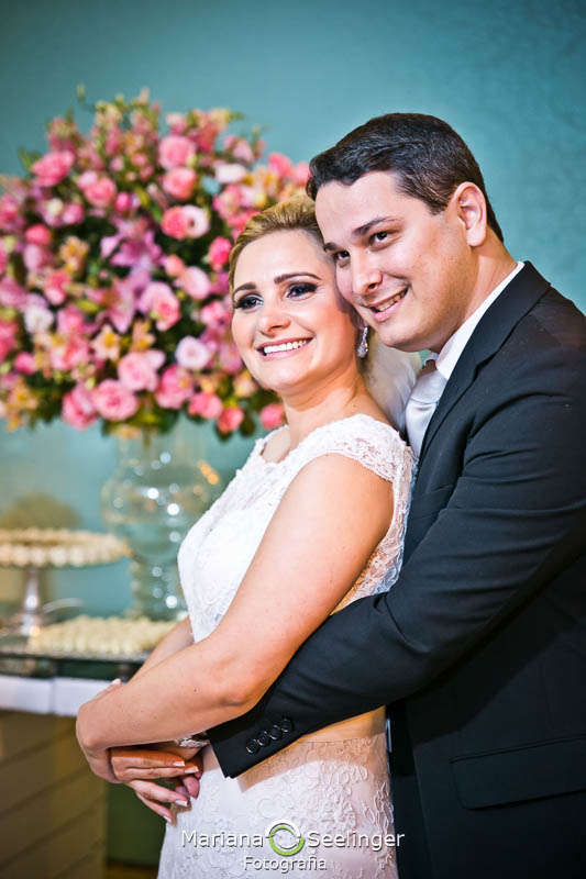 Noivos posando pra foto em frente a mesa de doces em casamento registrado por Mariana Seelinger Fotografia de Casamentos e Familias em Niterói RJ