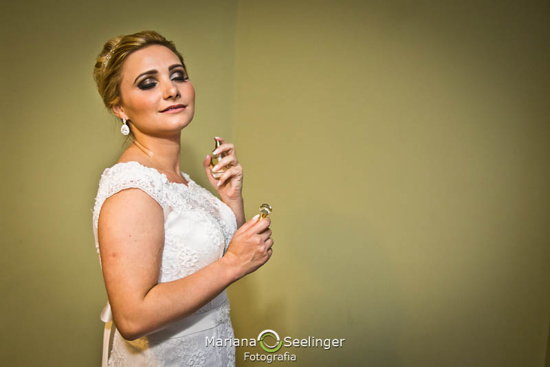 foto da noiva espirrando perfume no dia do casamento durante o making of realizado no hotel mercure orizzonte niteroi registro por mariana seelinger fotografia de casamentos e famílias Niteroi RJ