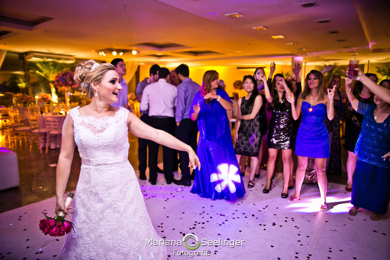 Fotografia da noiva em sua festa de casamento jogando o bouquet para suas convidadas em fotografia de Mariana Seelinger Fotógrafa de Casamentos em Niterói e RJ