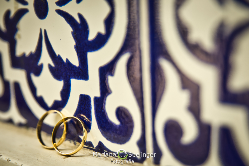 foto das alianças de casamento em fundo de azulejos portugueses azuis no alto da boa vista RJ em registro de Mariana Seelinger Fotografia