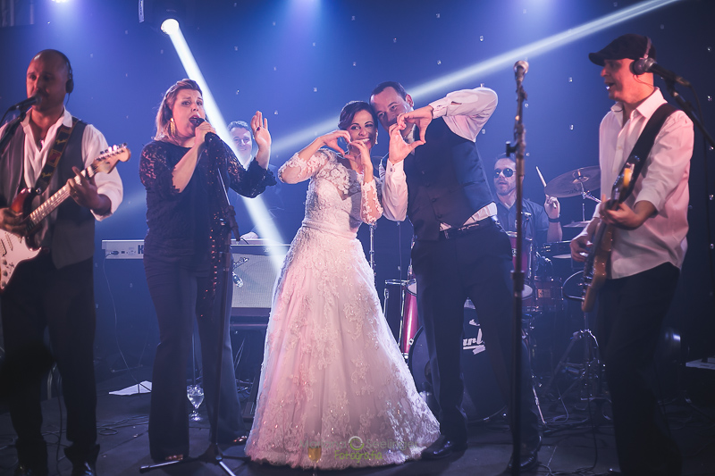 Noivos no palco junto com a banda em festa de casamento em niterói em casamento registrado por Mariana Seelinger Fotografia de Casamentos e Familias em Niterói RJ