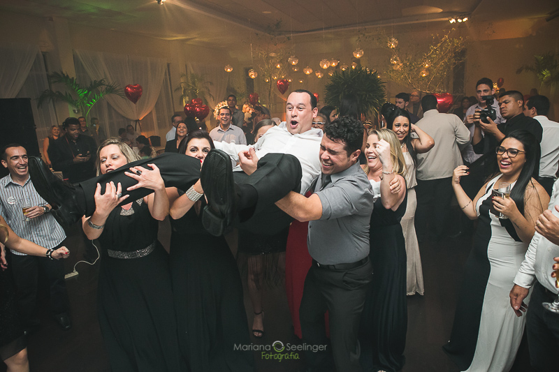 Convidados dos noivos levantando o noivo pro alto em casamento registrado por Mariana Seelinger Fotografia de Casamentos e Familias em Niterói RJ