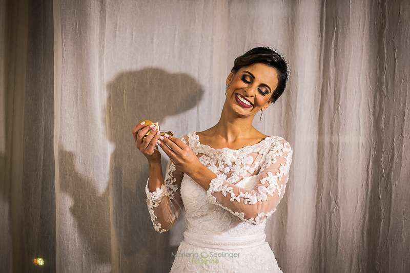 Noiva com vestido bordado se perfumando em seu making of no hotel mercure em casamento registrado por Mariana Seelinger Fotografia de Casamentos e Familias em Niterói RJ