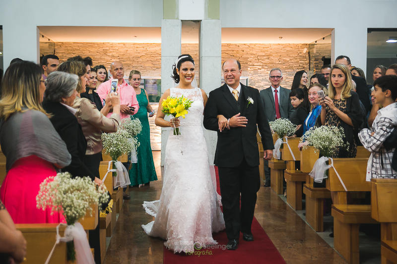 Noiva entrando na igreja com o bouquet de flores amarelas em casamento registrado por Mariana Seelinger Fotografia de Casamentos e Familias em Niterói RJ