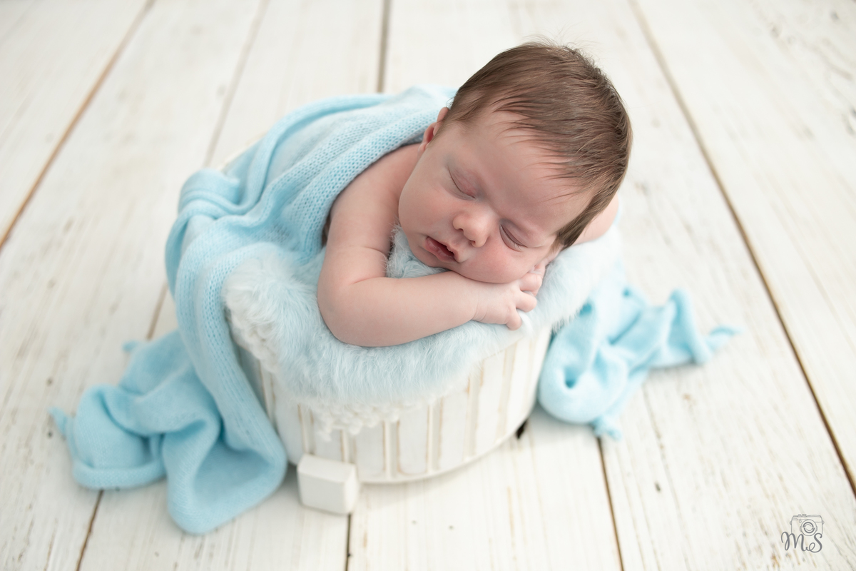Foto de bebê recém nascido estilo newborn em fundo de madeira em composicção branca cinza e azul