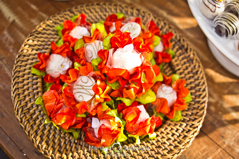 Doces finos de casamentos com forminhas de flores laranjas apoiados em bandeja de palha em fotografia de Mariana Seelinger Fotógrafa de Casamentos em Niterói e RJ