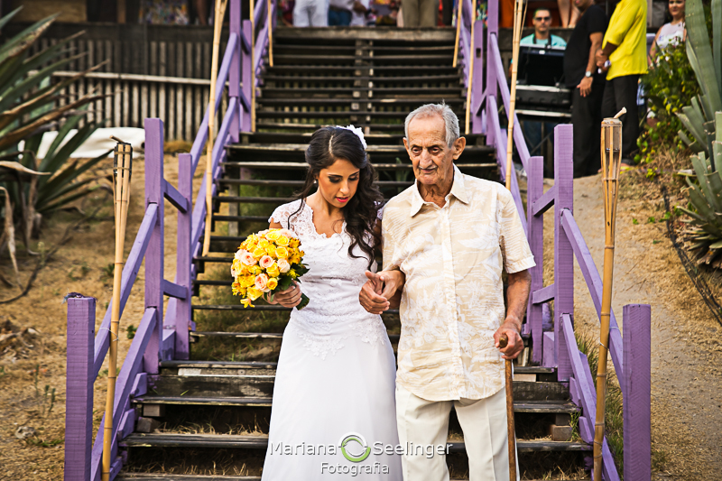 Noiva acompanhada de seu pai a caminho do altar em fotografia de Mariana Seelinger Fotógrafa de Casamentos em Niterói e RJ