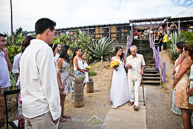Noiva sendo levada para o altar pelo seu pai em casamento na praia em fotografia de Mariana Seelinger Fotógrafa de Casamentos em Niterói e RJ