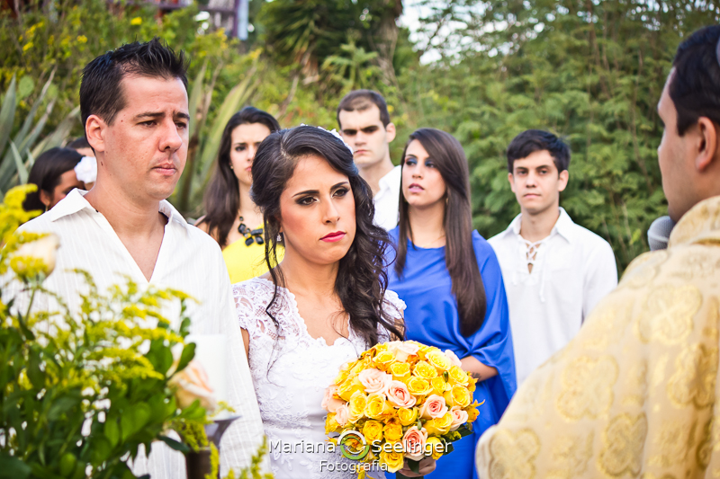 Noiva emocionada segurando o bouquet de fllores amarelas e brancas em fotografia de Mariana Seelinger Fotógrafa de Casamentos em Niterói e RJ