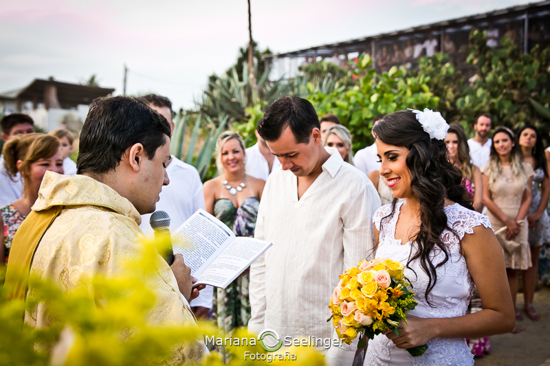 Noivo e noiva felizes emocionados ouvindo as palavras do celebrantes de casamento em fotografia de Mariana Seelinger Fotógrafa de Casamentos em Niterói e RJ