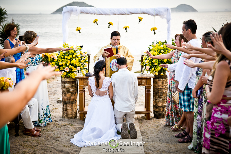 Casal recebendo a benção do celebrante na praia de camboinhas em fotografia de Mariana Seelinger Fotógrafa de Casamentos em Niterói e RJ