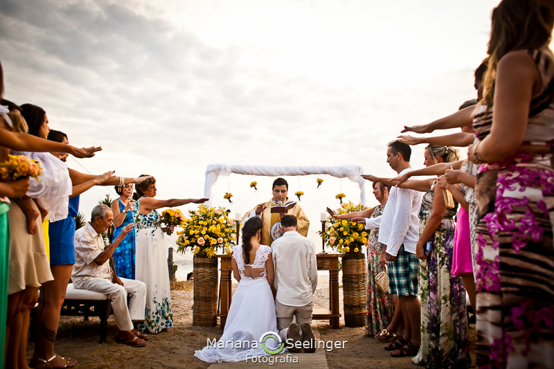 Noivos ajoelhados no altar decorado de flores verdes em fotografia de Mariana Seelinger Fotógrafa de Casamentos em Niterói e RJ