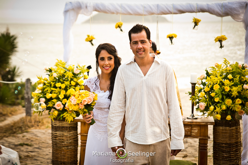 Noivos saindo do altar em praia de camboinhas em fotografia de Mariana Seelinger Fotógrafa de Casamentos em Niterói e RJ
