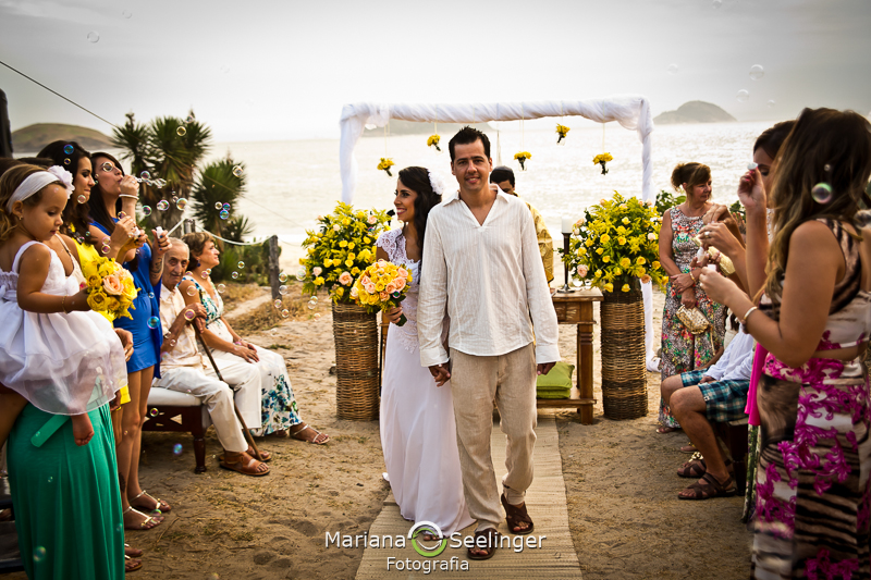 Noiva acenando para os familiares com o bouquet branco e amarelo em fotografia de Mariana Seelinger Fotógrafa de Casamentos em Niterói e RJ