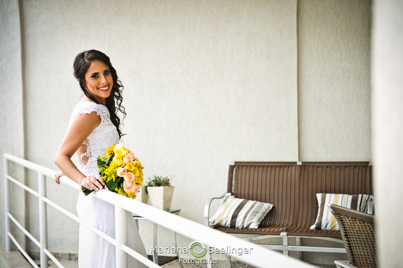 Fotografia da noiva com o bouquet na sacada da pousada na praia de camboinhas em fotografia de Mariana Seelinger Fotógrafa de Casamentos em Niterói e RJ