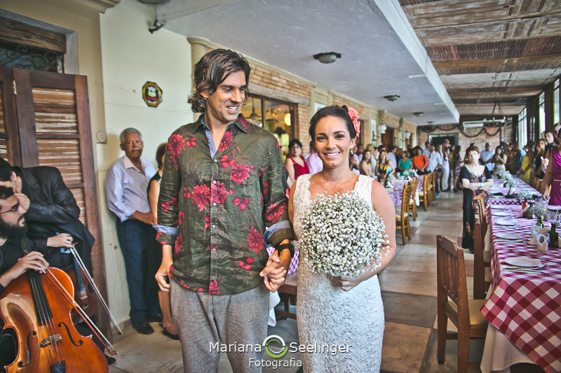 Noivo admirando sua noiva no altar feito de prancha de surf em fotografia de Mariana Seelinger Fotógrafa de Casamentos em Niterói e RJ