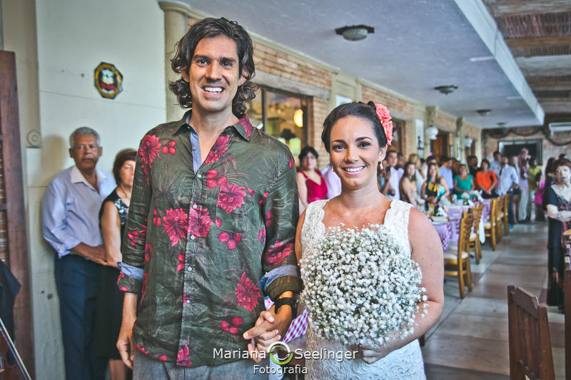 Noivos feliz se casando no altar feito de prancha de surf em fotografia de Mariana Seelinger Fotógrafa de Casamentos em Niterói e RJ