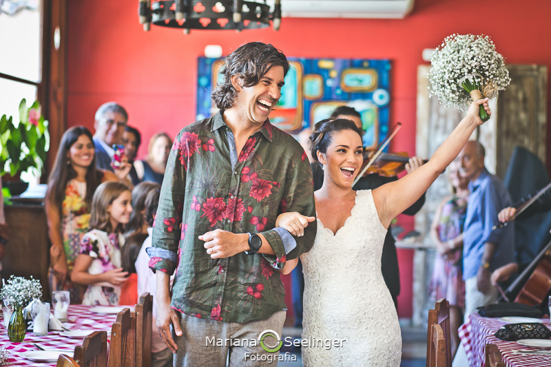 Noiva e noivo muitos feliz acenando para seus convidados em fotografia de Mariana Seelinger Fotógrafa de Casamentos em Niterói e RJ