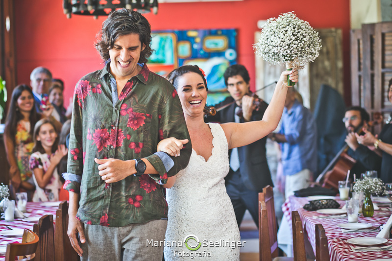 Noiva acenando para seus familiares com o bouquet na mão em fotografia de Mariana Seelinger Fotógrafa de Casamentos em Niterói e RJ