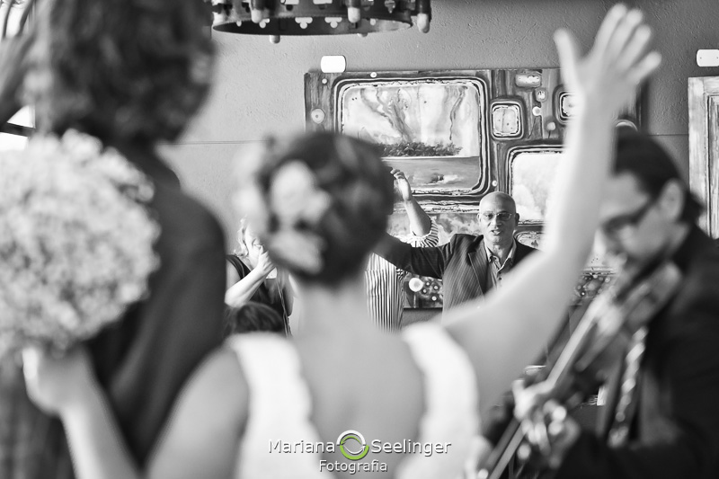 Casal de noivos acenando para o celebrante de seu casamento em fotografia de Mariana Seelinger Fotógrafa de Casamentos em Niterói e RJ
