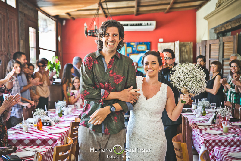 Noivo e noiva saindo do altar feito de pranchas de surf em fotografia de Mariana Seelinger Fotógrafa de Casamentos em Niterói e RJ