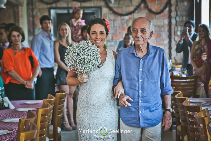 Noiva entrando no restaurante italiano acompanhada de seu pai em fotografia de Mariana Seelinger Fotógrafa de Casamentos em Niterói e RJ
