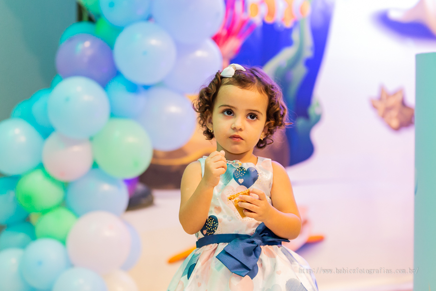 Foto de aniversariante em sua festa de 2 anos comendo doce com a decor fundo do mar no pipas club maringa