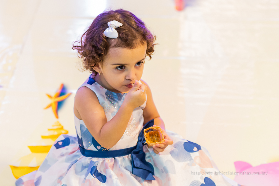 Foto de aniversariante em sua festa de 2 anos comendo doce com a decor fundo do mar no pipas club maringa