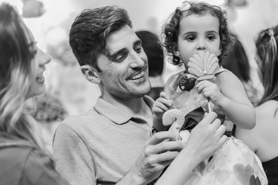 Fotografia da aniversariante comedo doces no colo do papai