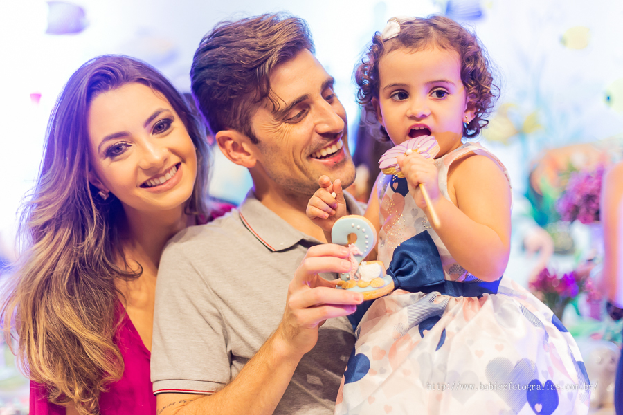 Fotografia da aniversariante comedo doces no colo do papai
