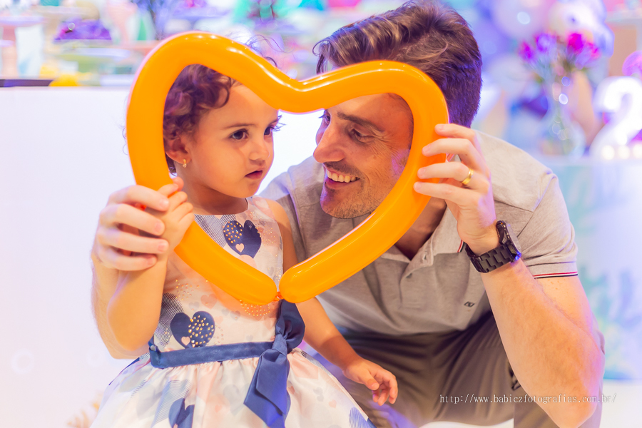 Aniversariante brincando com um coração de balao com o papai na sua festa de aniversario